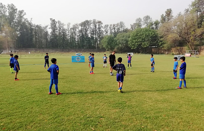 Students getting footbal training by their coach on the ground
