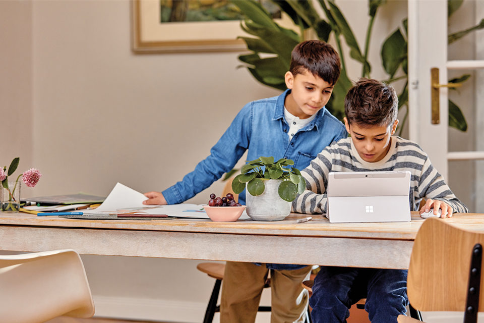 Young male students working at home on Surface Go