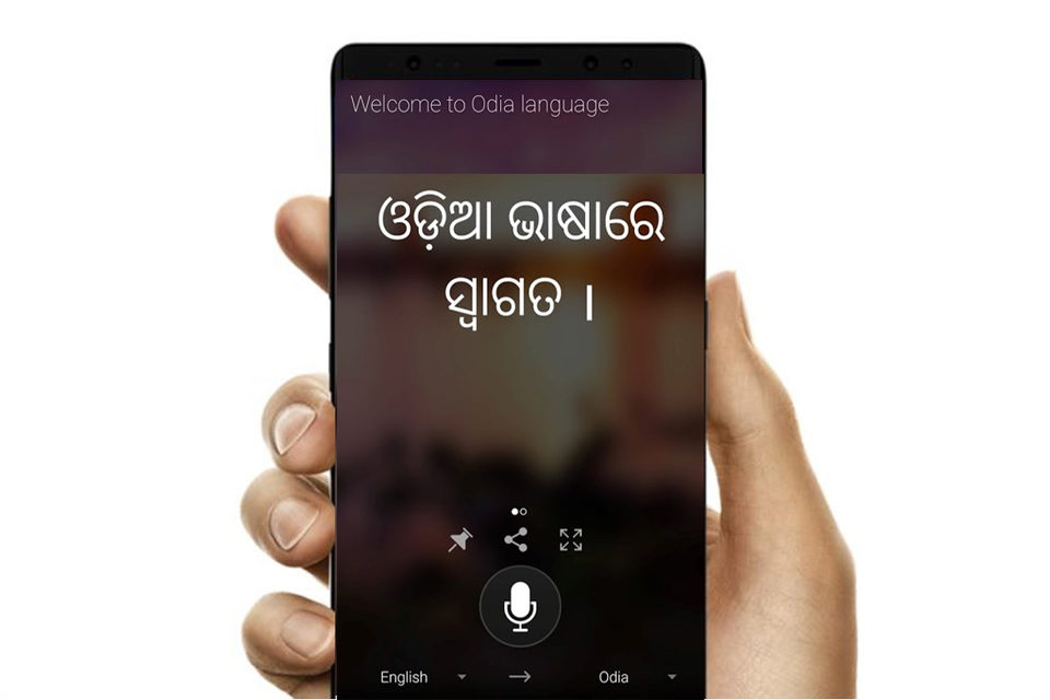 A smartphone user accessing Microsoft Translator app for Odia translation. The screen reads 'Welcome to Odia language' and shows the translated text below, along with options to pin, share, enlarge, speak and switch to another language