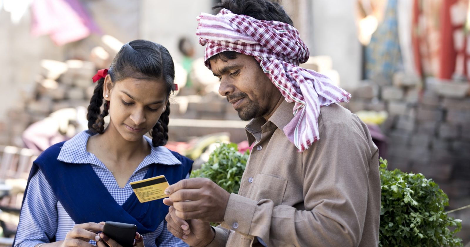 a photo of a man holding a credit card and a girl using a phone to make an online transaction
