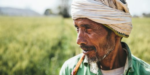 Photo of a farmer with a green field in the background