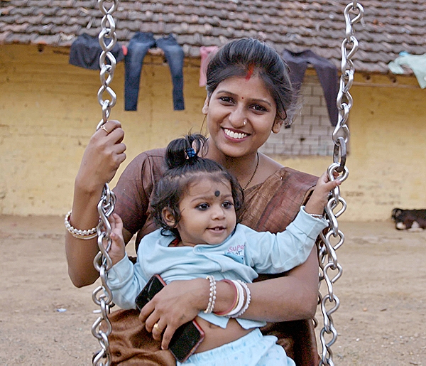 Photo of a woman with her kid on a sitting swing.