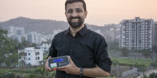 Photo of a man smiling at the camera holding a gadget