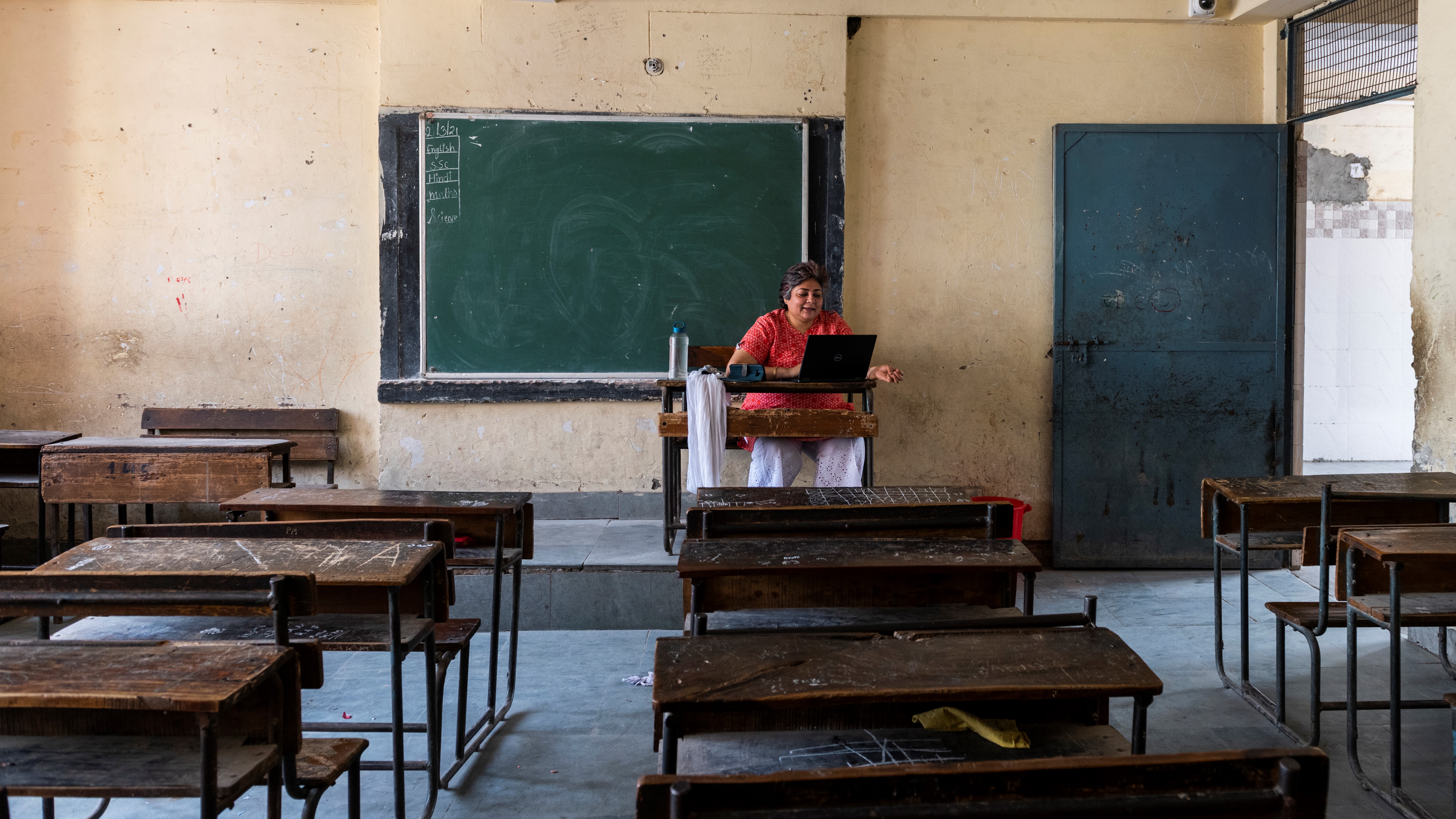 a woman sitting in an empty classroom