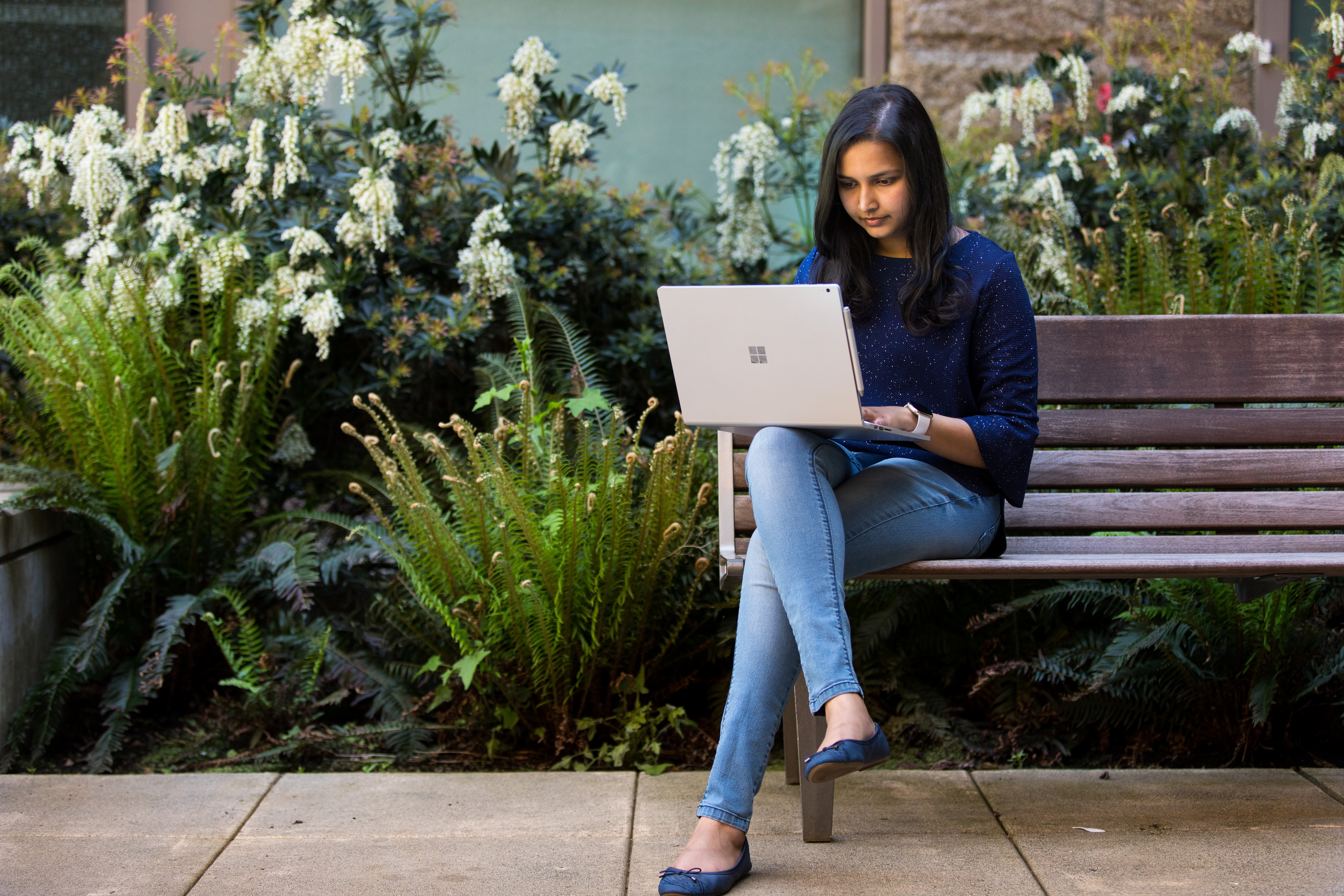 Photo of a woman sitting on a bench and working on a laptop