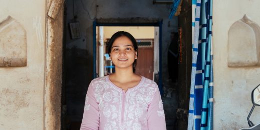 Photo of a girl smiling at the camera standing at a doorway