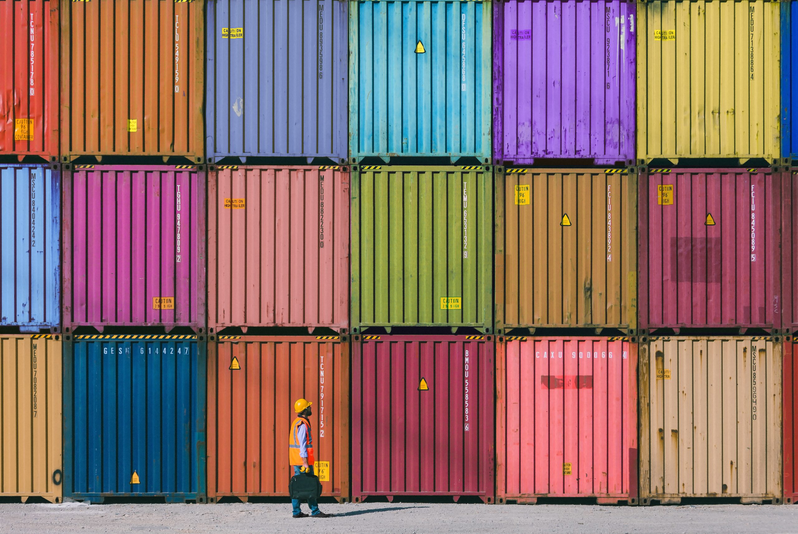 a man standing in front of a colorful stack of shipping containers