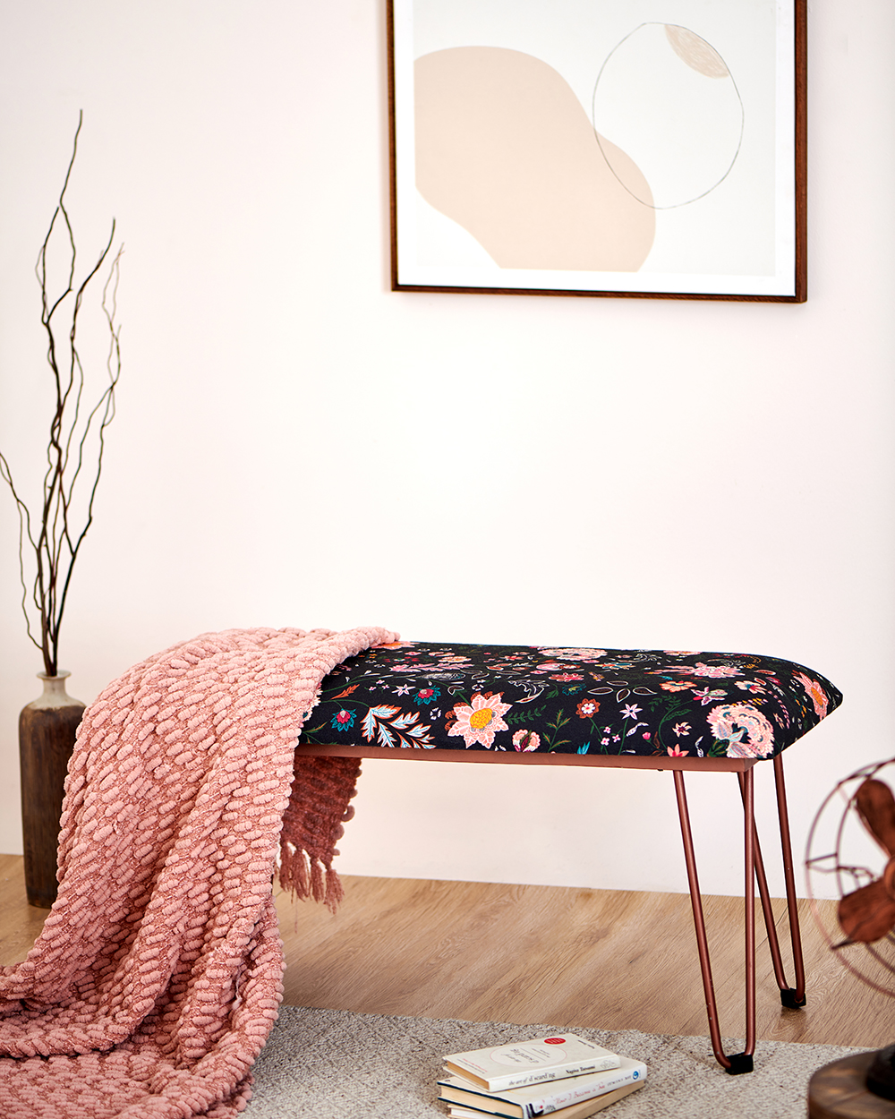 a colorful upholstered bench with a pink throw on it