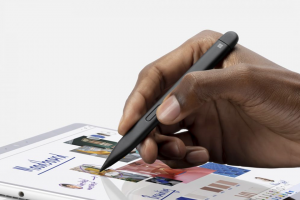 A hand holding a stylus pen against a Surface Pro 8