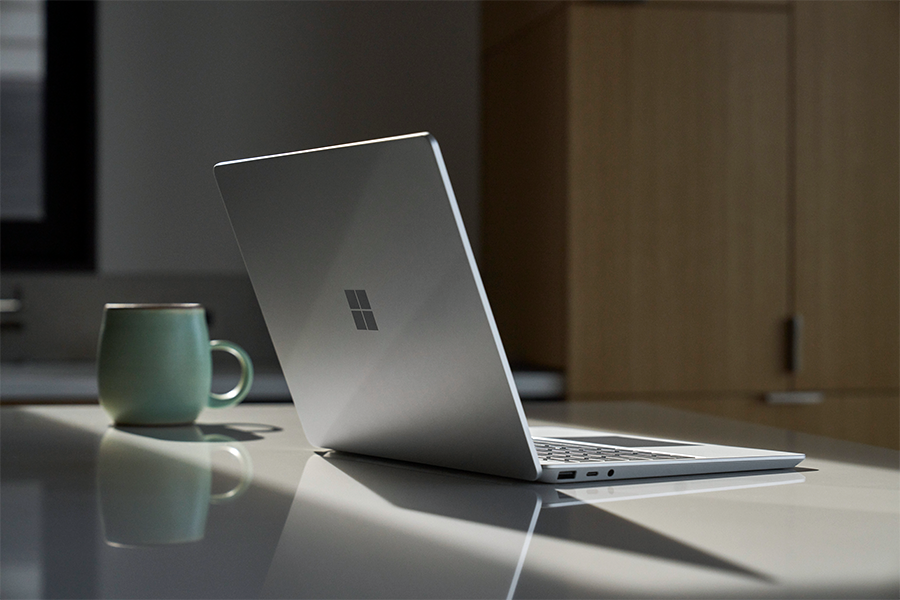 a photo of surface laptop go 2 with its lid open along with a coffee mug