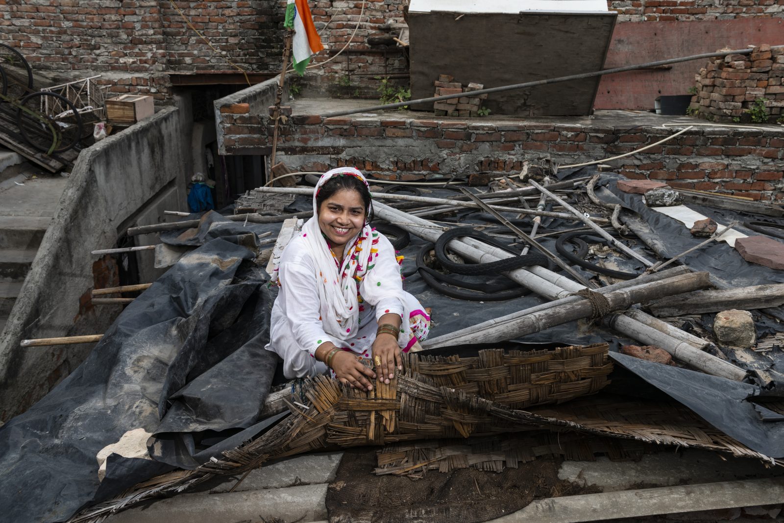 a woman sitting on the roof of her tin shack home displaying a low-cost solution for keeping her house cool