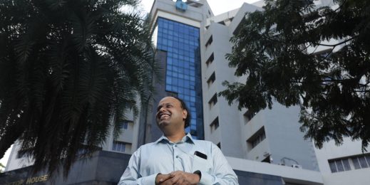 a man who is blind standing in front of a building with SBI's logo on top