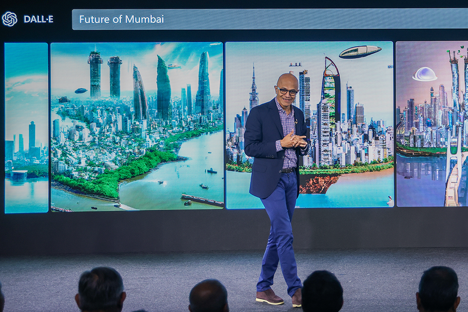 a man wearing giving a keynote with the screen behind displaying Dall-E's interpretation of future of Mumbai