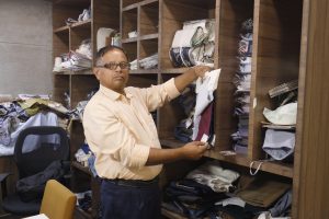 Photo of a spectacled man holding up a book of fabric samples for the camera