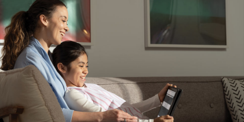 mom and child smiling while looking at tablet