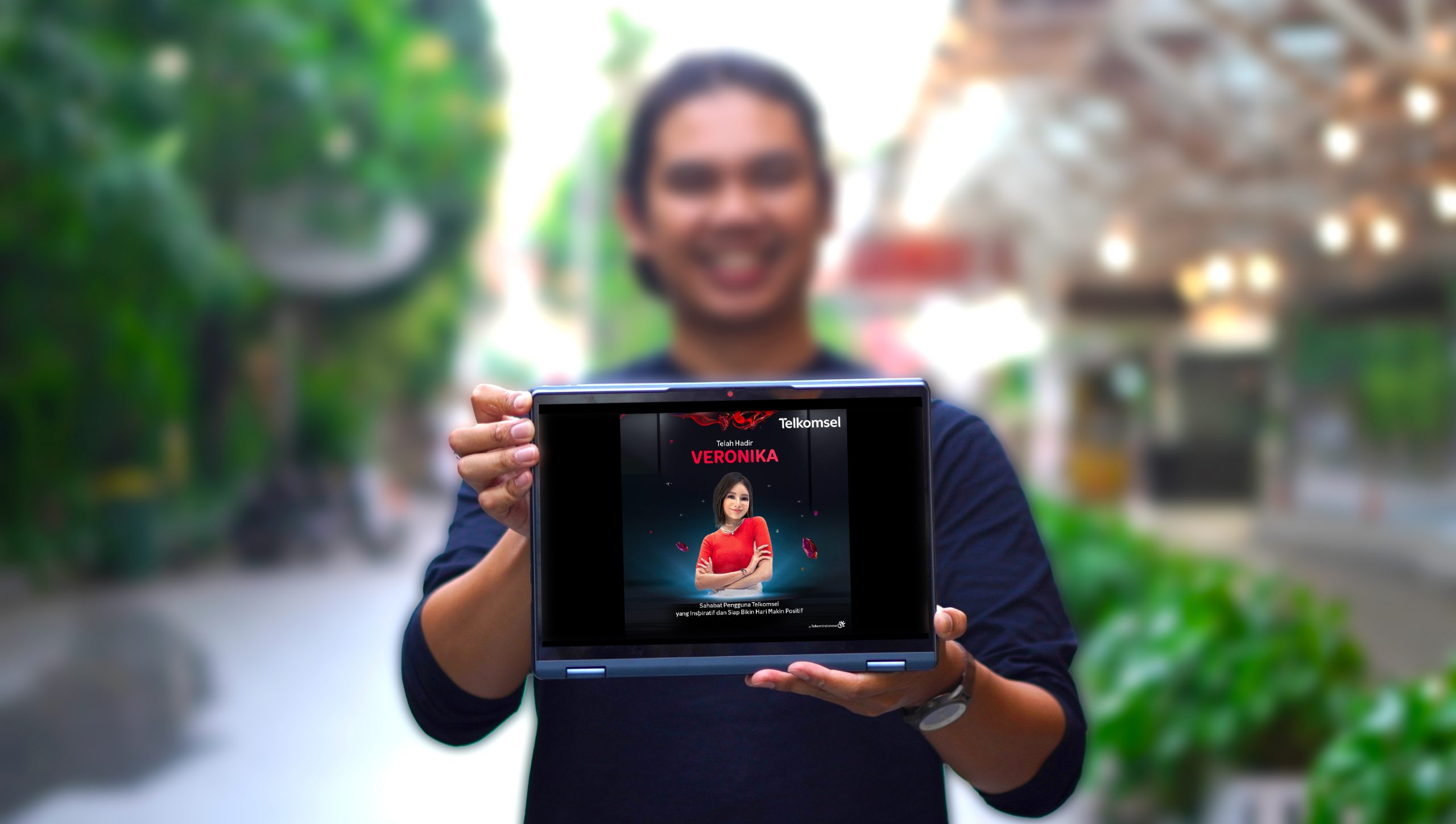 A man holding tablet that showcases Telkomsel virtual assistant