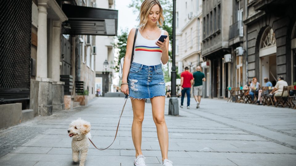 Young woman with her dog, enjoy in walk in shaded summer city street