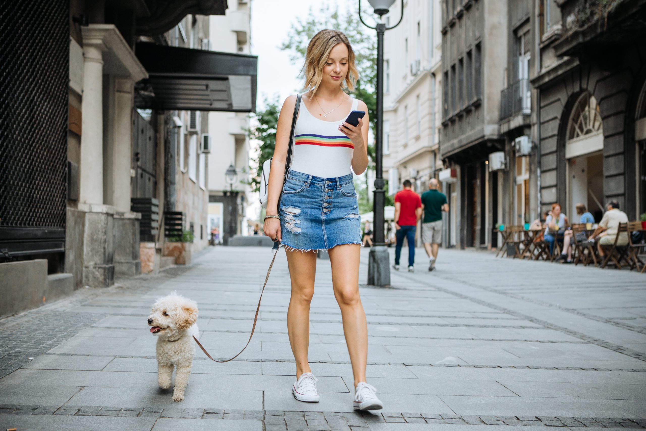 Young woman with her dog, enjoy in walk in shaded summer city street