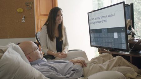 Используя ножную мышь, Eye Control для Windows 10 и функцию преобразования текста в речь, Отто Кнок может общаться с клиентами и семьей, в том числе с дочерью, запечатленной на этом снимке.