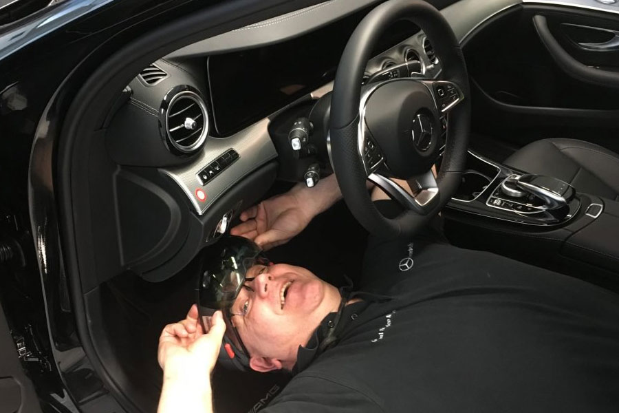 Сотрудник Mercedes в очках HoloLens проводит осмотр под приборной панелью автомоибля