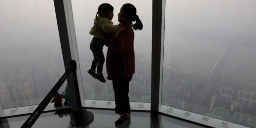 Женщина, держащая на руках дочь и смотрящая через окно на Сеул в день сильнейшего загрязнения воздуха. Getty Images.