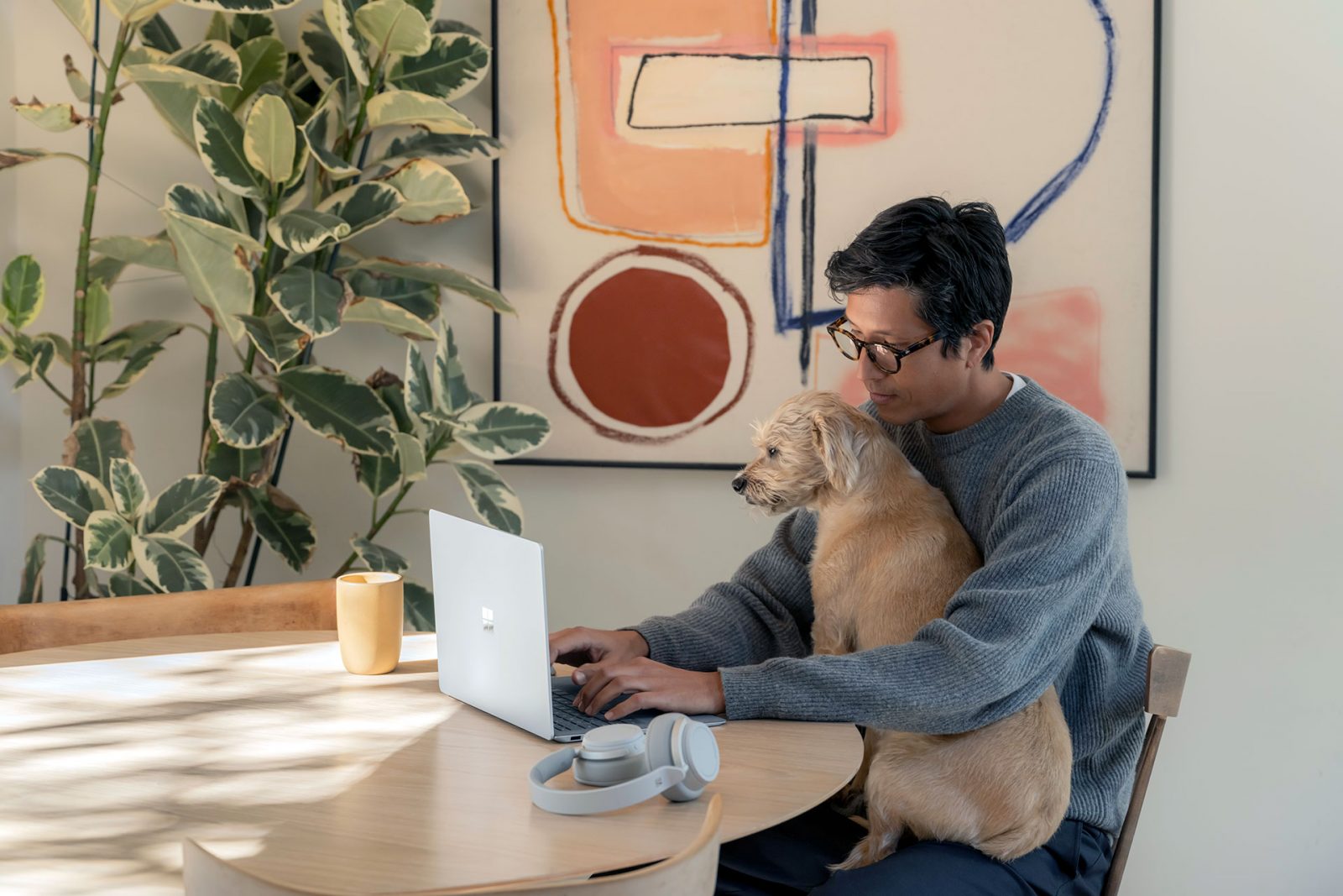 Мужчина работает дома за ноутбуком с собакой на коленях
