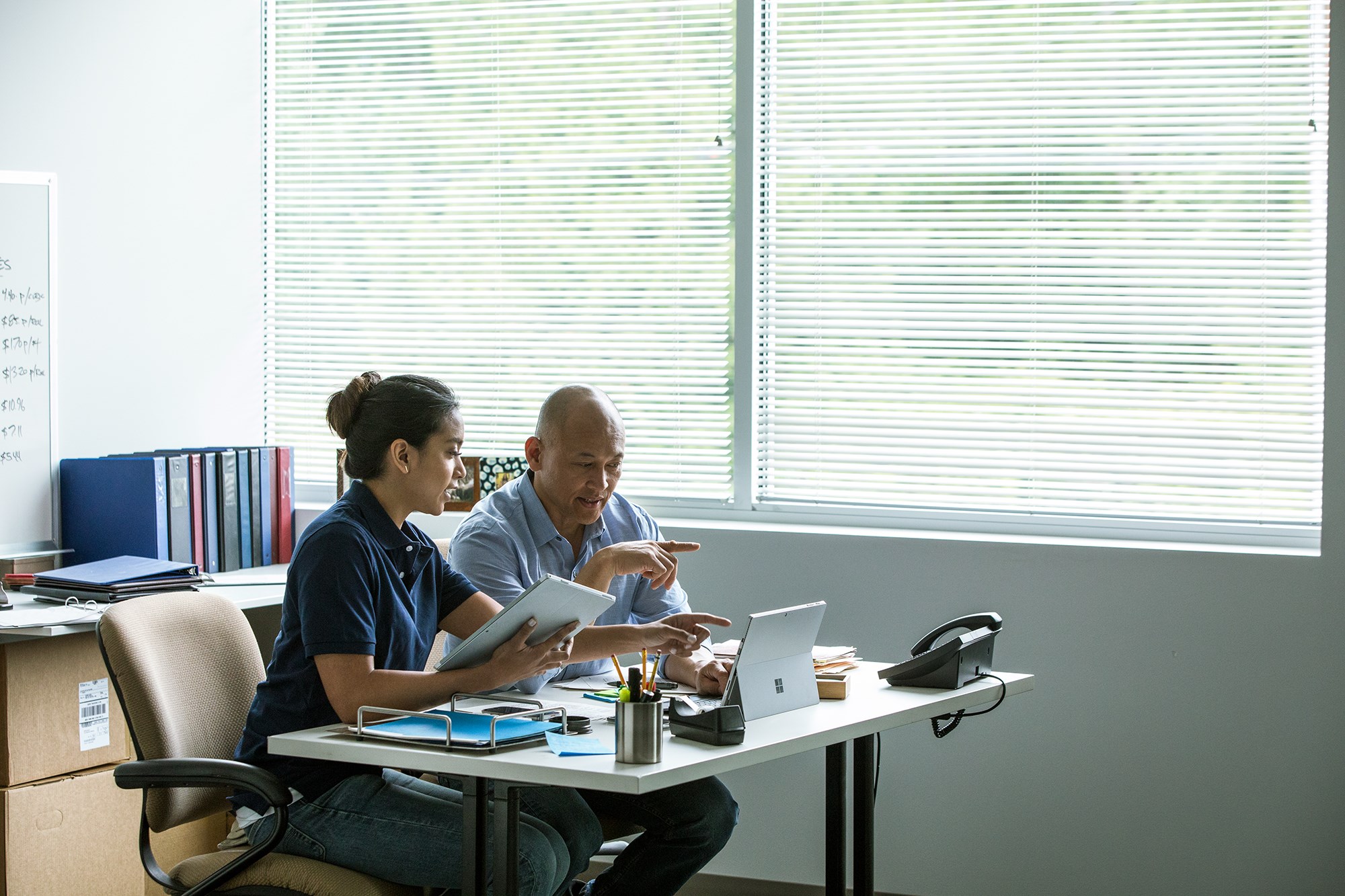 Two people in an office with two Surface devices