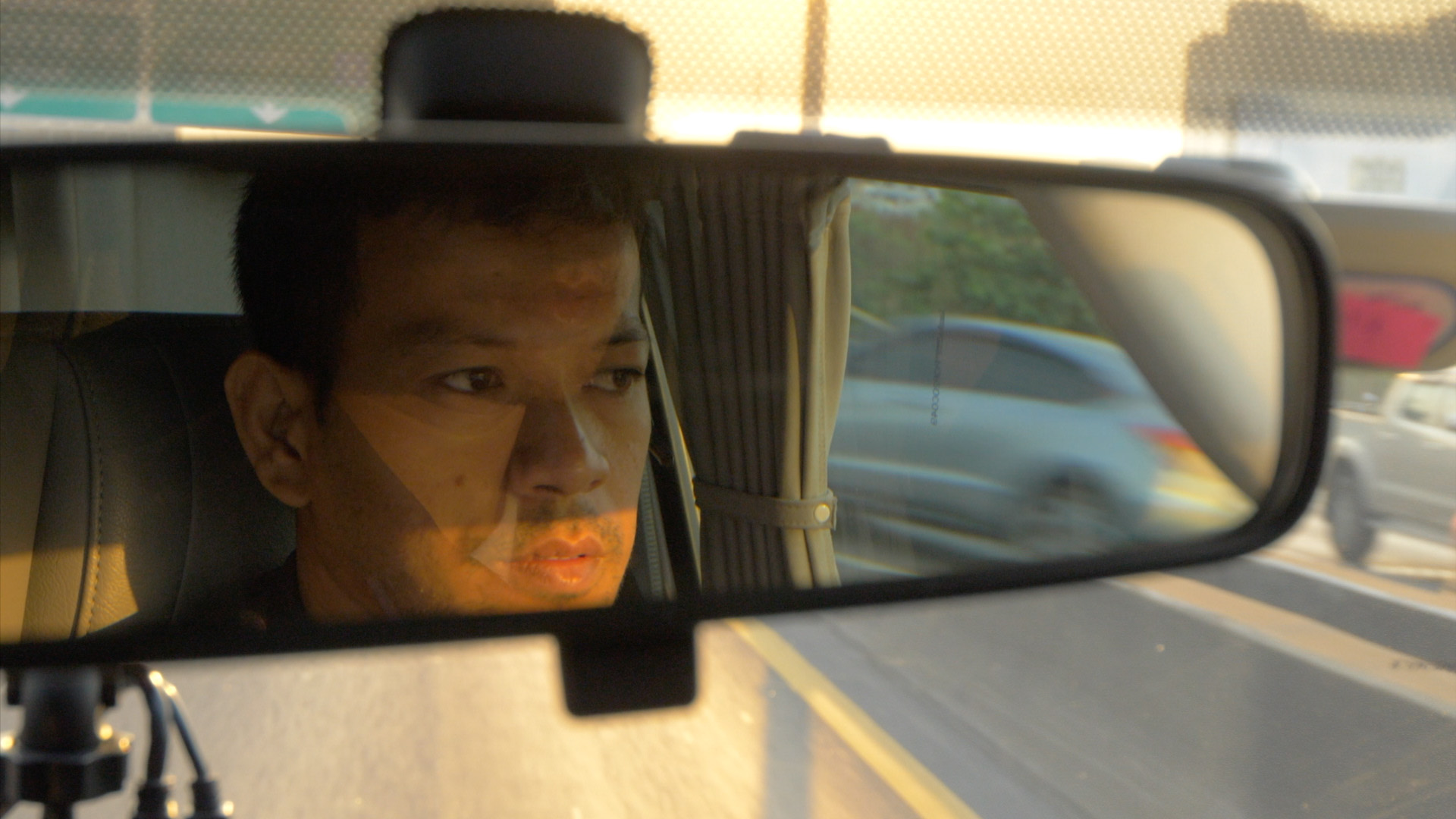 Face of man driving car reflected on rear-view mirror