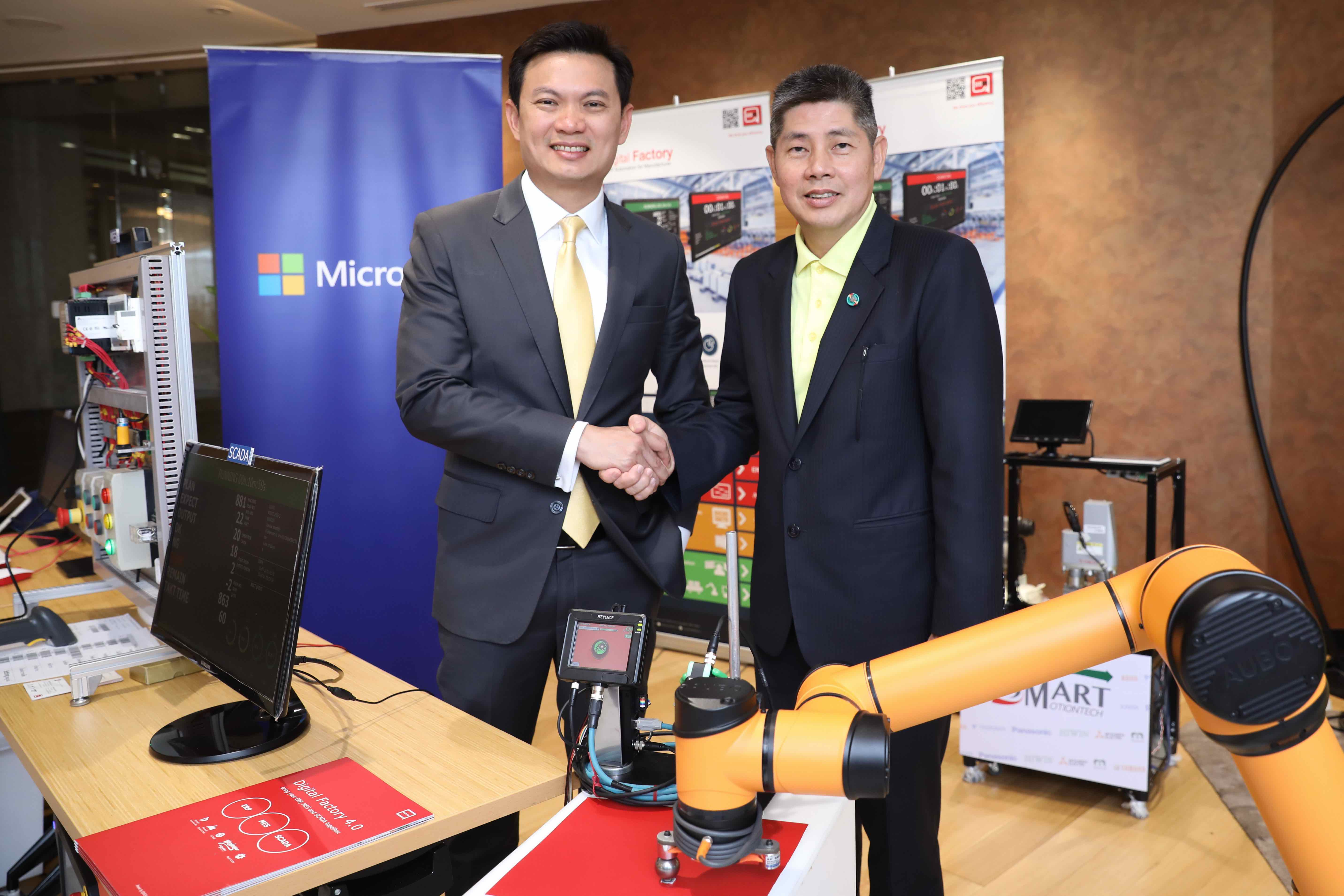 Two men standing behind robot arm and in front of Microsoft banner