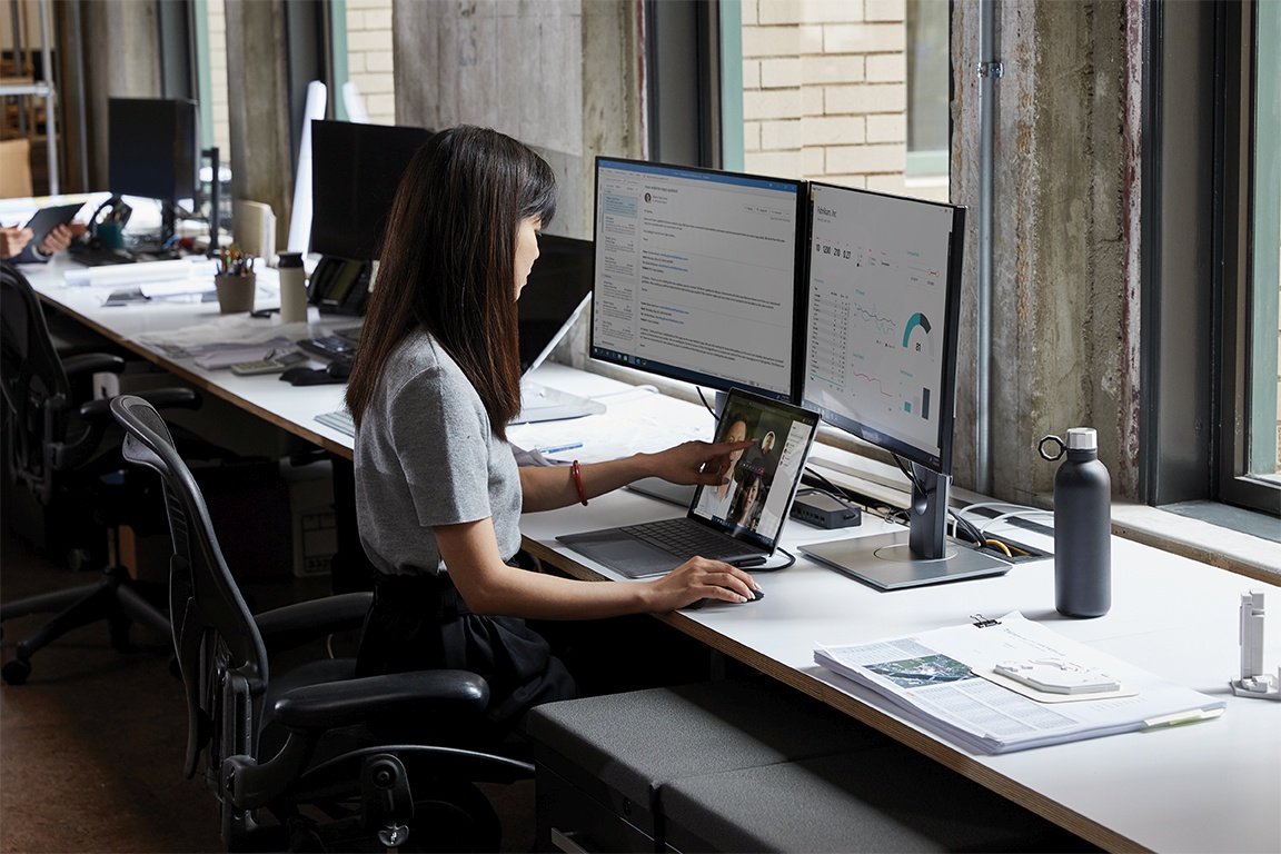 Woman using a laptop with two monitors