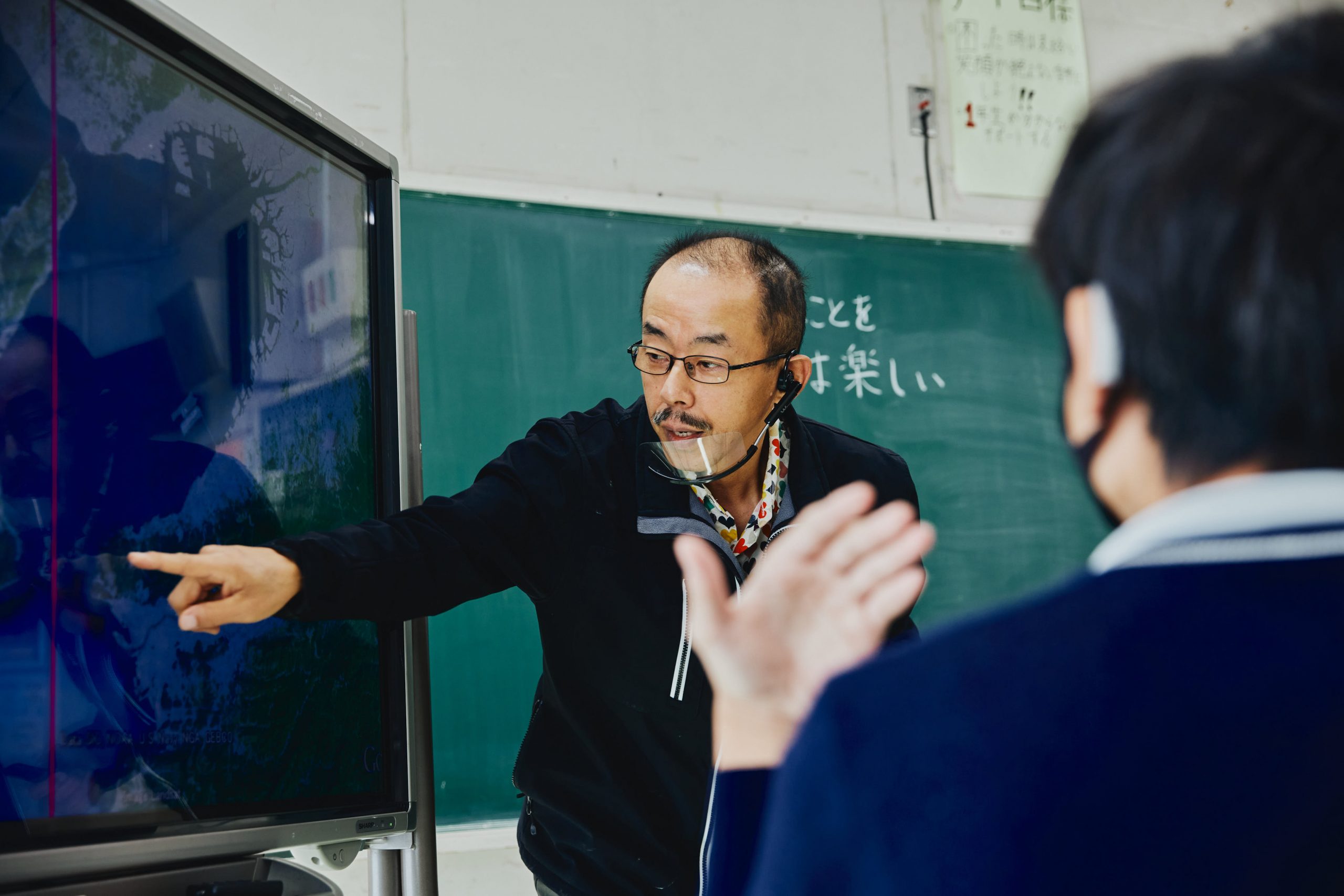 大阪府立堺聴覚支援学校で PowerPoint の教材を映しながら社会を教える稲葉先生