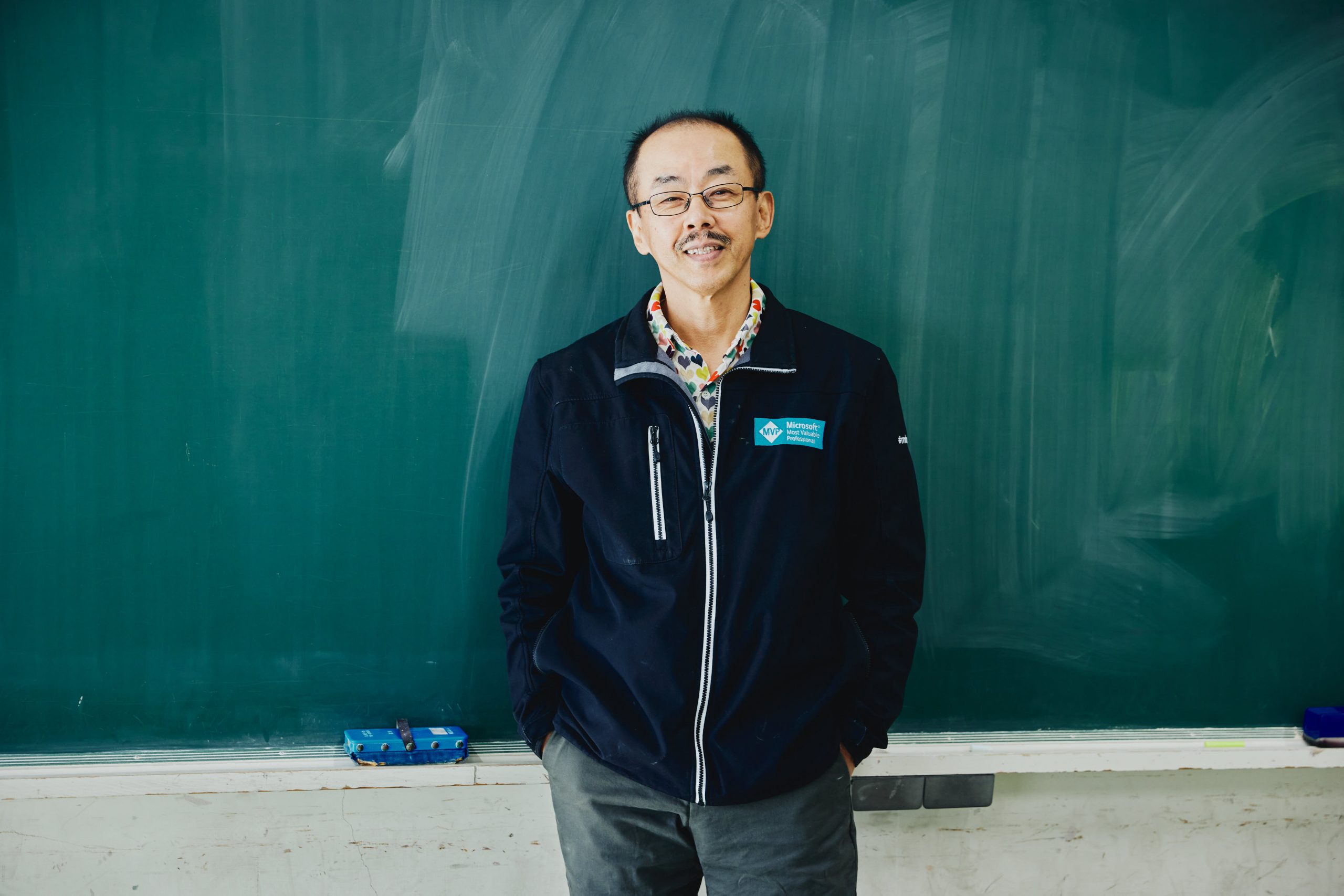 生徒たちがきれいにしてくれた黒板の前で笑顔を見せる稲葉先生
