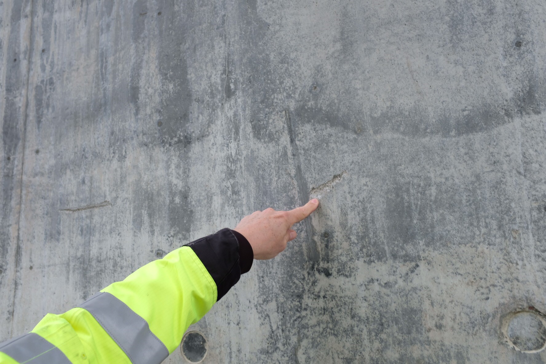 A hand pointing toward a concrete wall