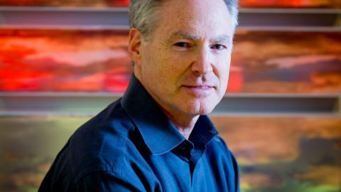 Eric Horvitz sits in front of a multi-colored background