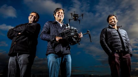 Researchers Shital Shah, Ashish Kapoor and Debadeepta Dey, stand with an autonomous drone in the background