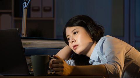 asian business woman sitting at desk sleepy working overtime late night. indoors office background