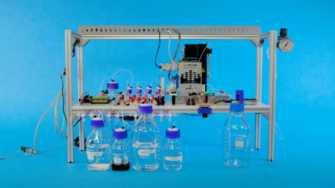 The automated DNA data storage system in a metal frame, in front of glass beakers