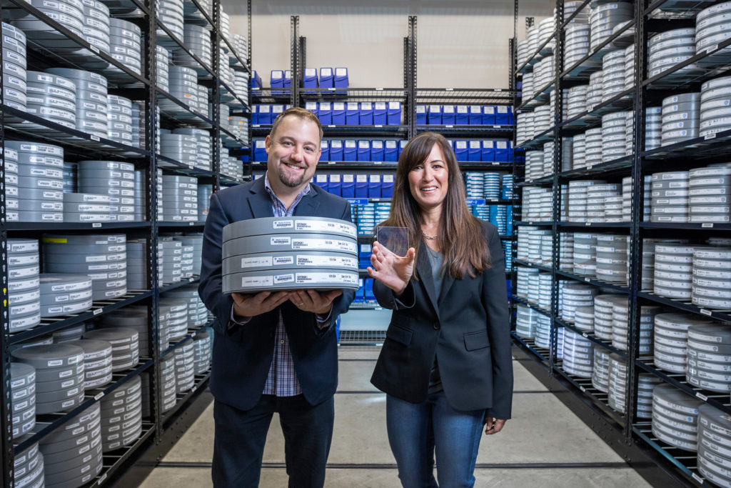 In a Warner Brothers cold storage room, Brad Collar, holding film cannisters, and Vicky Colf, holding a piece of silica glass, both containing the 1978 movie 'Superman'