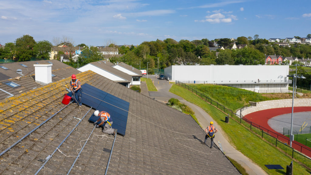 Men on a school roof installing solar panels