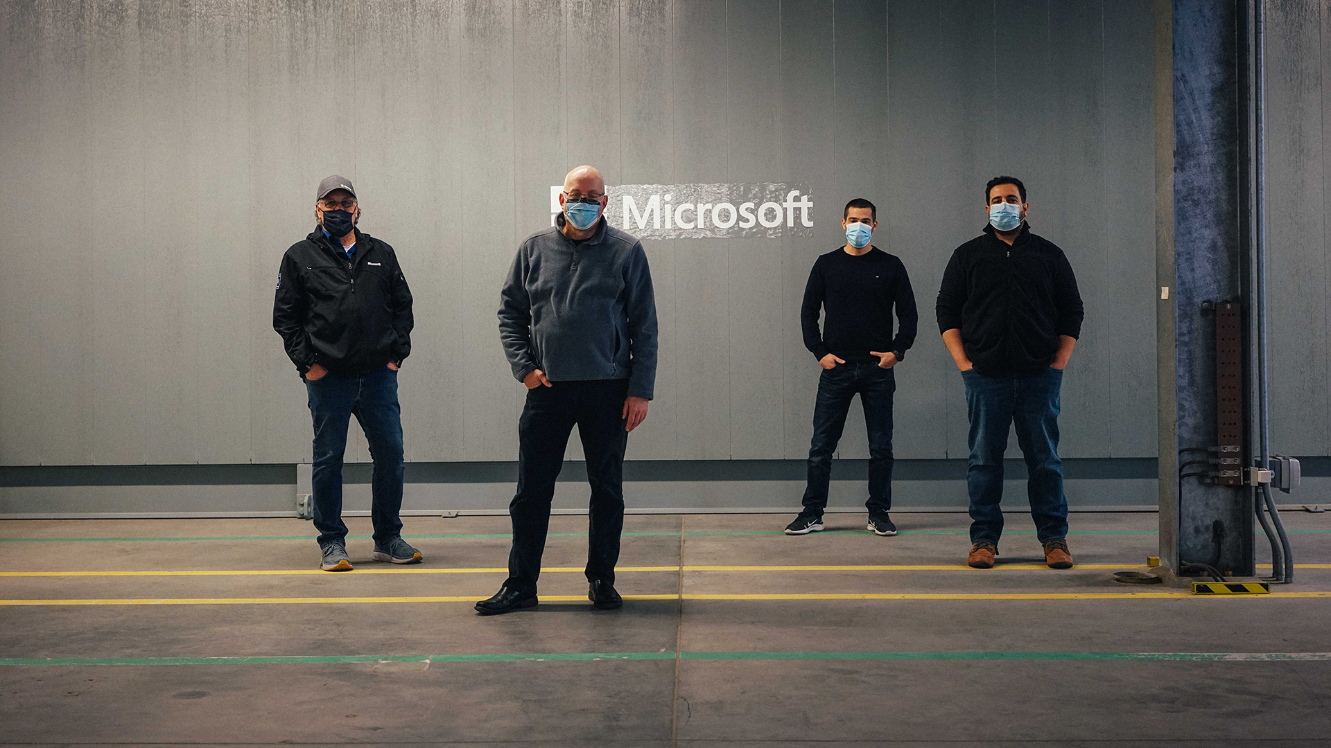 Four team members stand in front of a building housing the liquid cooling tank