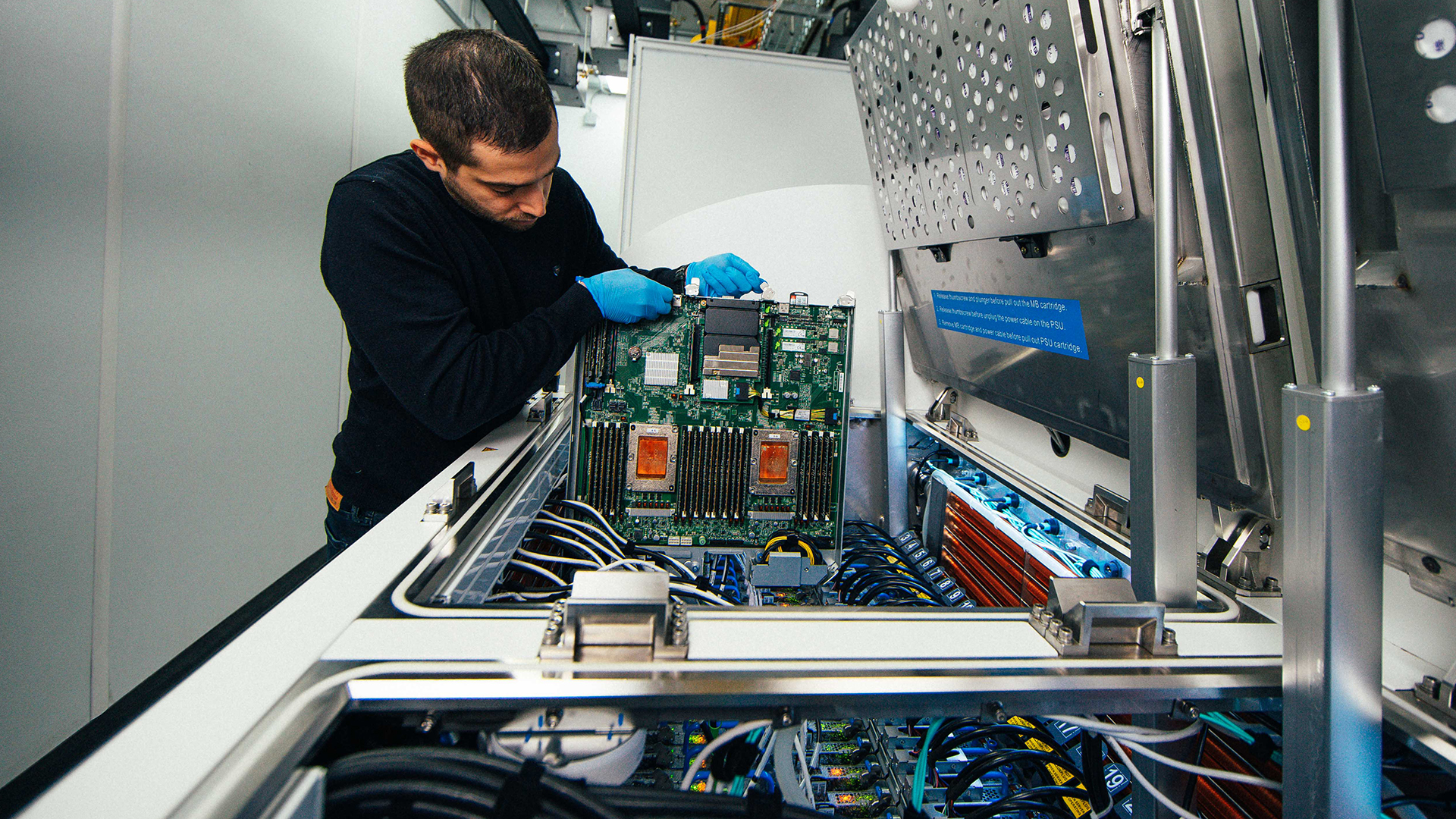 Ioannis Manousakis removes a server blade from a two-phase immersion cooling tank