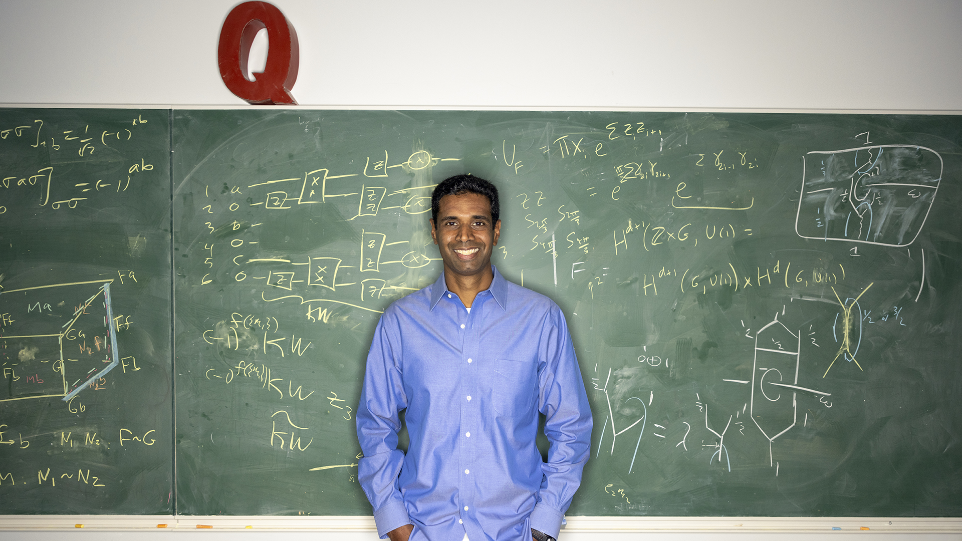 A man stands in front of a chalkboard