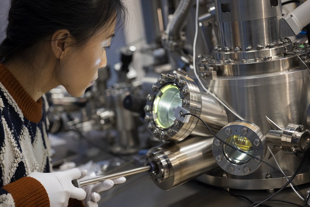 A woman looks into a piece of quantum material lab equipment