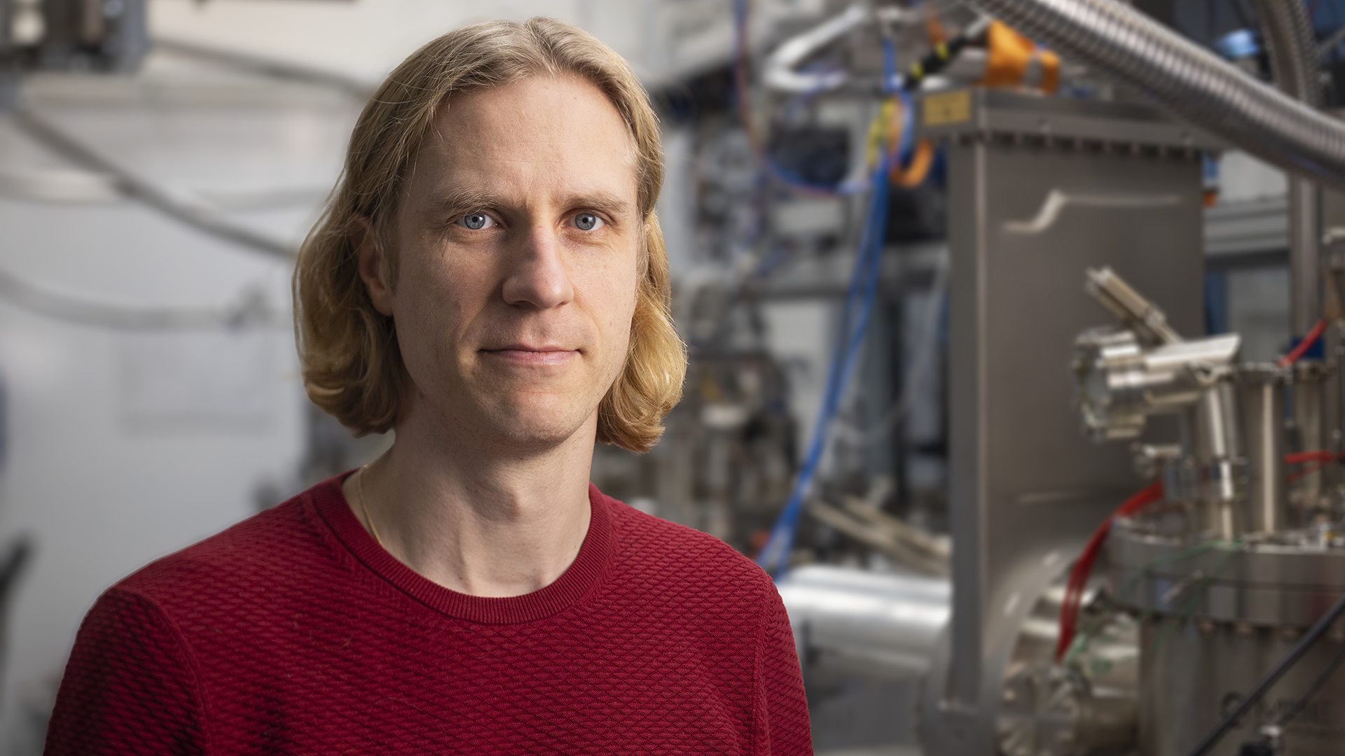 A man stands in front of quantum material lab equipment