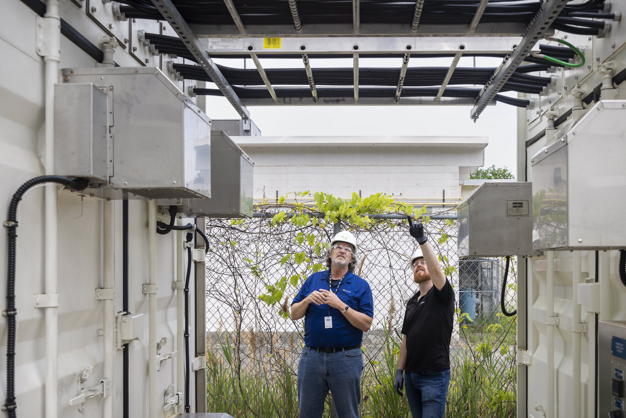 Mark Monroe, a principal infrastructure engineer on Microsoft’s team for datacenter advanced development, and Sean James, Microsoft’s director of datacenter research, stand between the two shipping containers and discuss the three-megawatt hydrogen fuel cell system