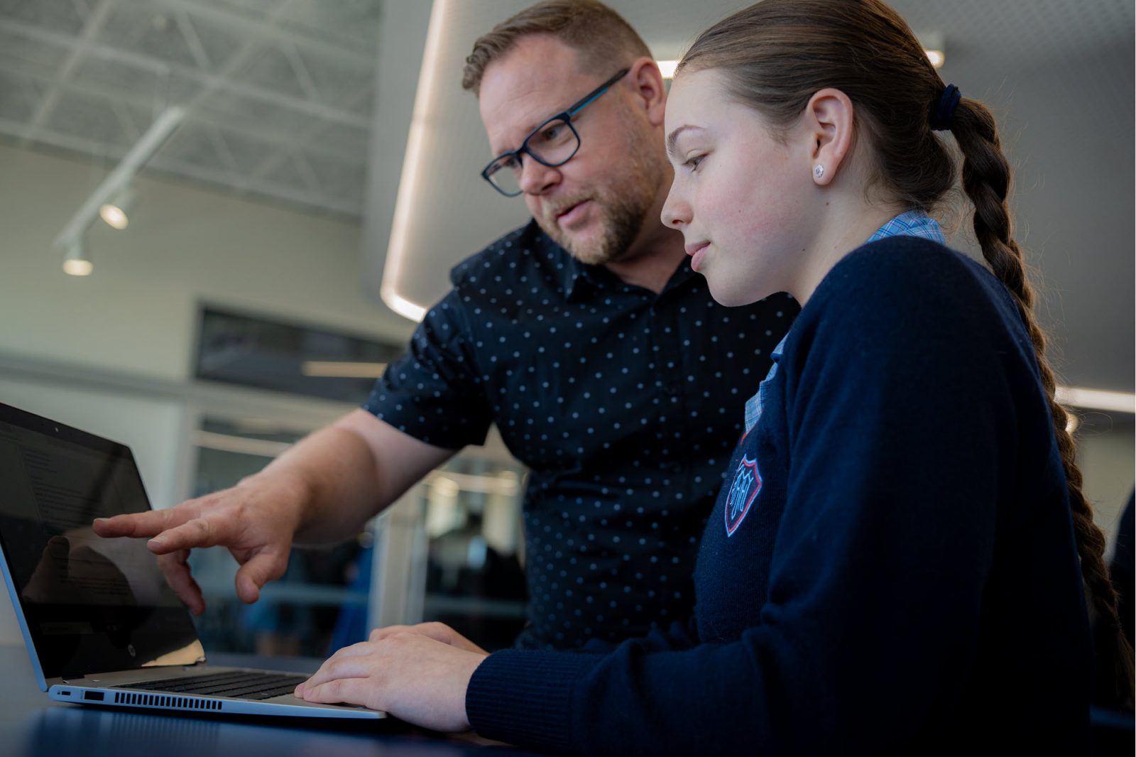 Enseignant aidant un élève qui utilise EdChat sur un ordinateur.