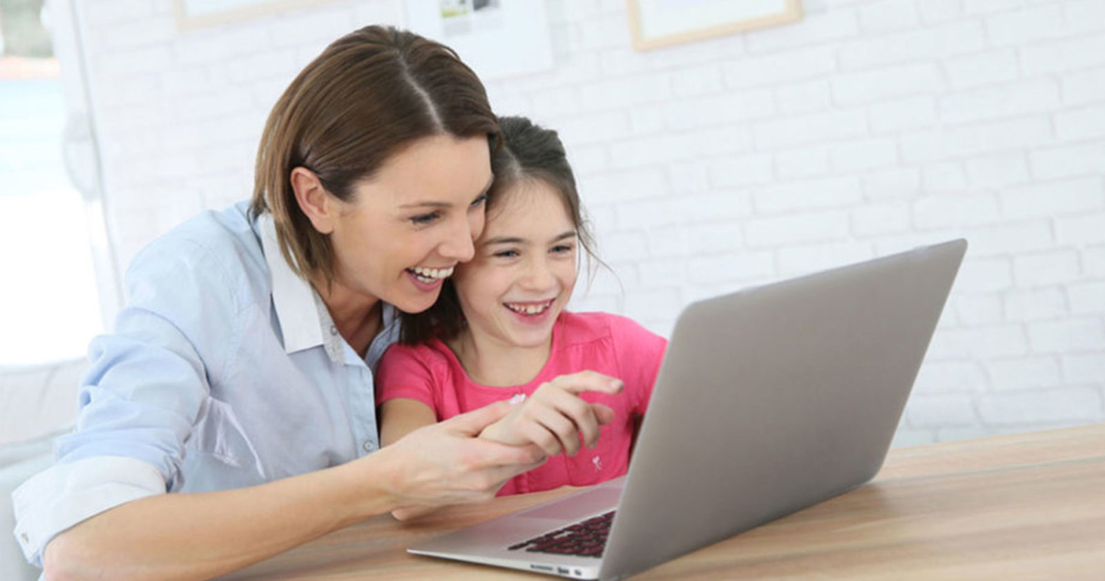 تكمل الأم وابنتها مهام المدرسة عبر الإنترنت من خلال جهاز كمبيوتر محمول.