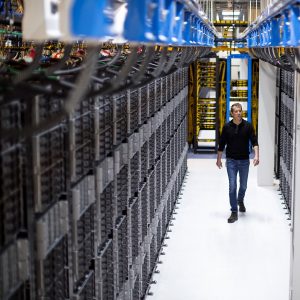 Man walks past racks of servers in a datacenter