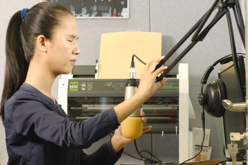 Young woman with impaired vision repositioning a microphone