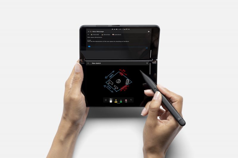 A person holding a black Surface Duo 2 phone and a black Surface pen